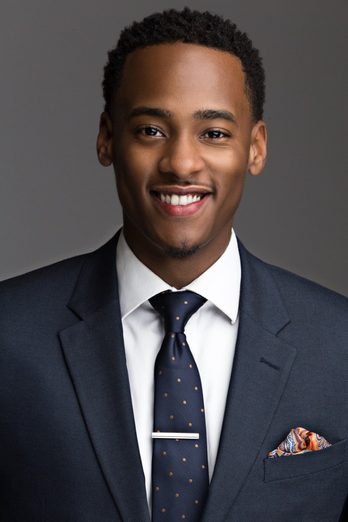 Portrait of Stephon Dingle in a navy suit against a gray background.